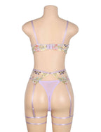 Back view of purple floral lingerie set with adjustable hook closure, sheer mesh briefs, garters, and leg loops