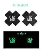 Two black pasties with 'FUCK ME!' text, one in daylight and one in dark conditions.
